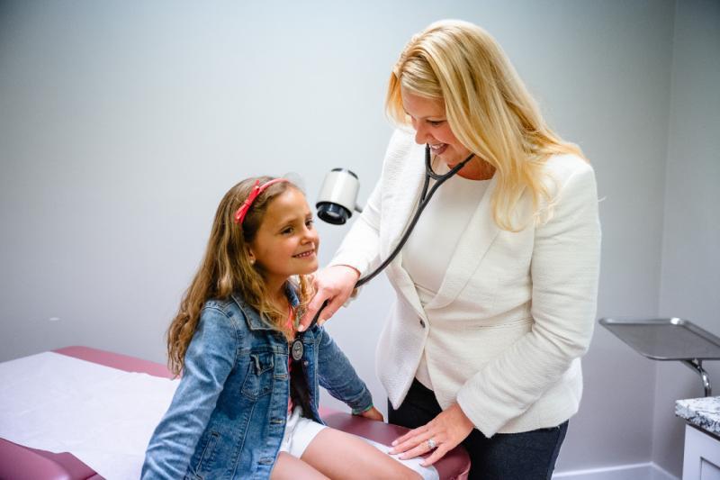 a provider listening to the heartbeat of a young girl